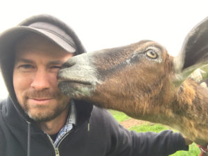 A goat licks Colin Crowley's face.