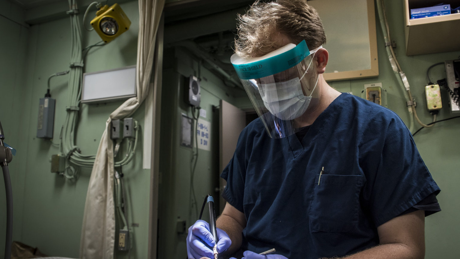 A U.S. Navy officer wears a medical face shield during a teeth cleaning. (Courtesty: U.S. Naval Forces Central Command/U.S. Fifth Fleet)
