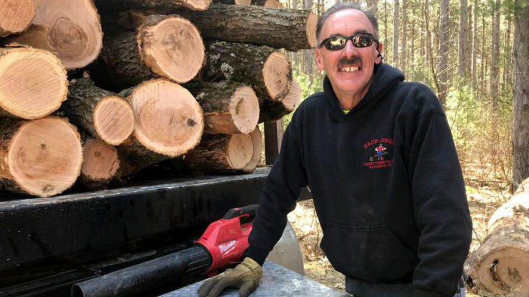 Man standing next to cut logs