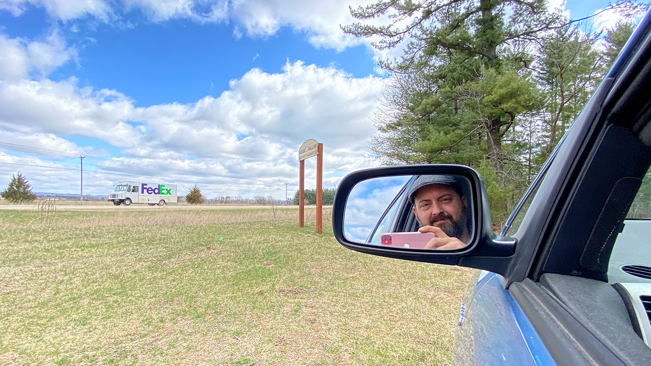 Reflection of man in car's side mirror holding cell phone