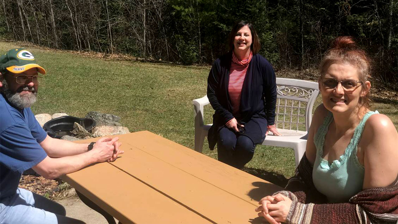 A man and two women sitting around a picnic table