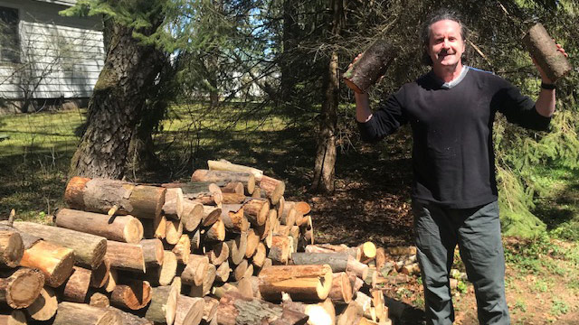 Man standing next to pile of split wood
