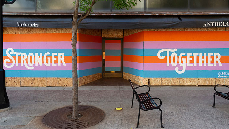 A boarded-up storefront has been repainted to say stronger together.