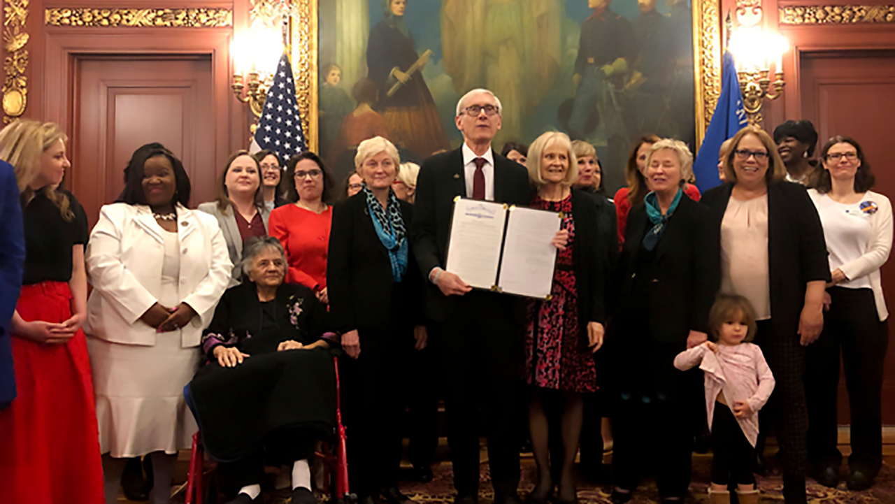 Governor Tony Evers of Wisconsin stands with his wife, legislators and dignitaries