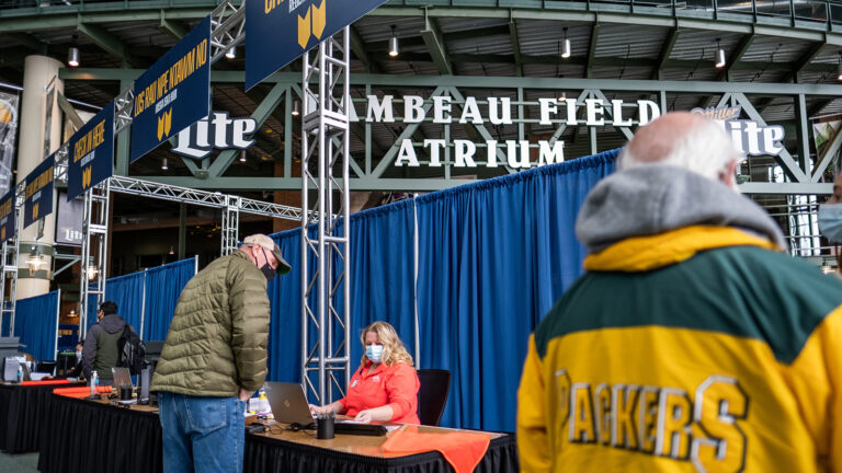 Patients stand in line to sign up for coronavirus vaccinations at a community clinic at Lambeau Field.