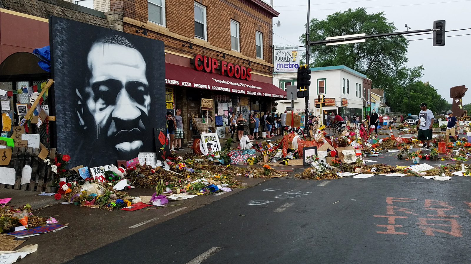 Flowers and artwork on the street and sidewalk in front of Cup Foods grocery store in Minneapolis