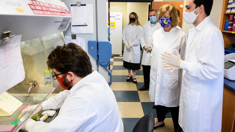 Sen. Tammy Baldwin and scientists watch research in a laboratory.
