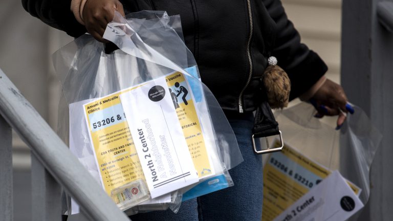 Hands holding bags filled with coronavirus vaccination information