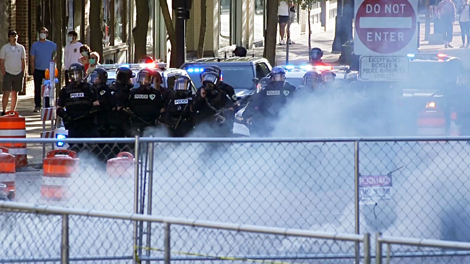 Temporary fencing and tear gas in front of a line of police officers