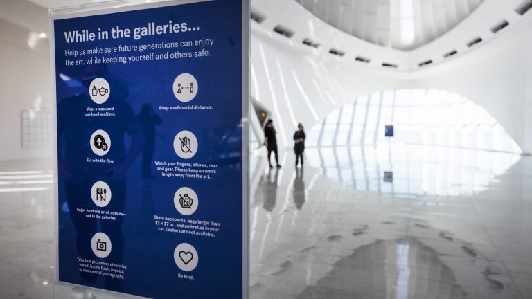 A sign instructs on safety protocols near the entrance to the Milwaukee Art Museum A sign instructs on safety protocols near the entrance to the Milwaukee Art Museum