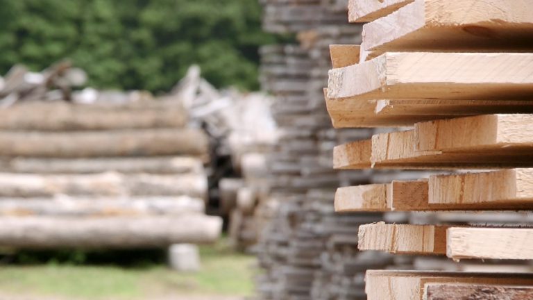 Stack of lumber in focus in foreground with stacks of lumber and timber in blurred background