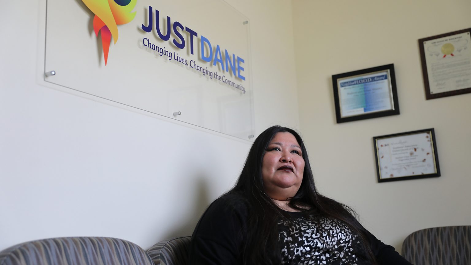 Janie Ocejo sits under a JustDane office sign