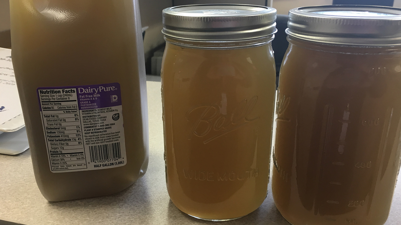 Half-gallon milk jug and two canning jars are filled with brown, opaque water.