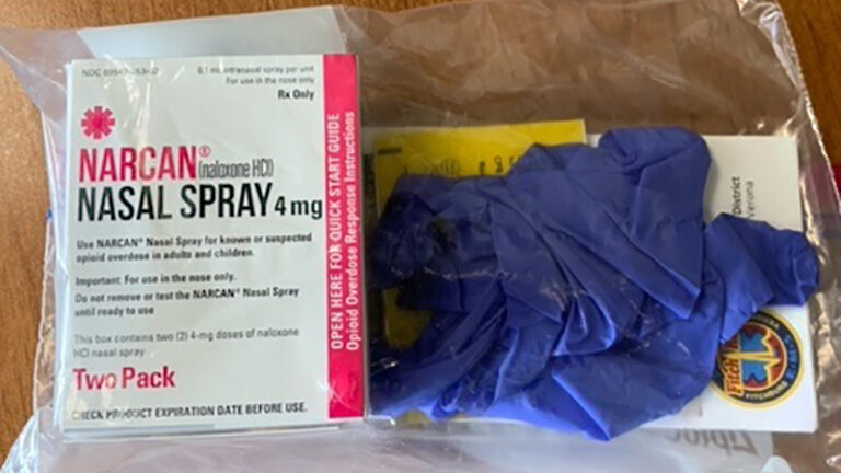 Narcan kit with medication, gloves and other supplies in bag on table