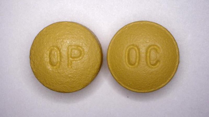 Two yellow oxycontin pills sitting on a white surface