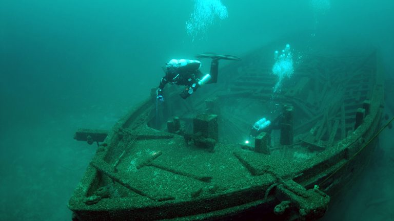 Underwater photo of divers looking down at a shipwreck