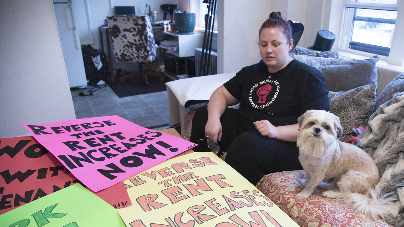 Karianne and a dog sit on a couch facing table with protest signs