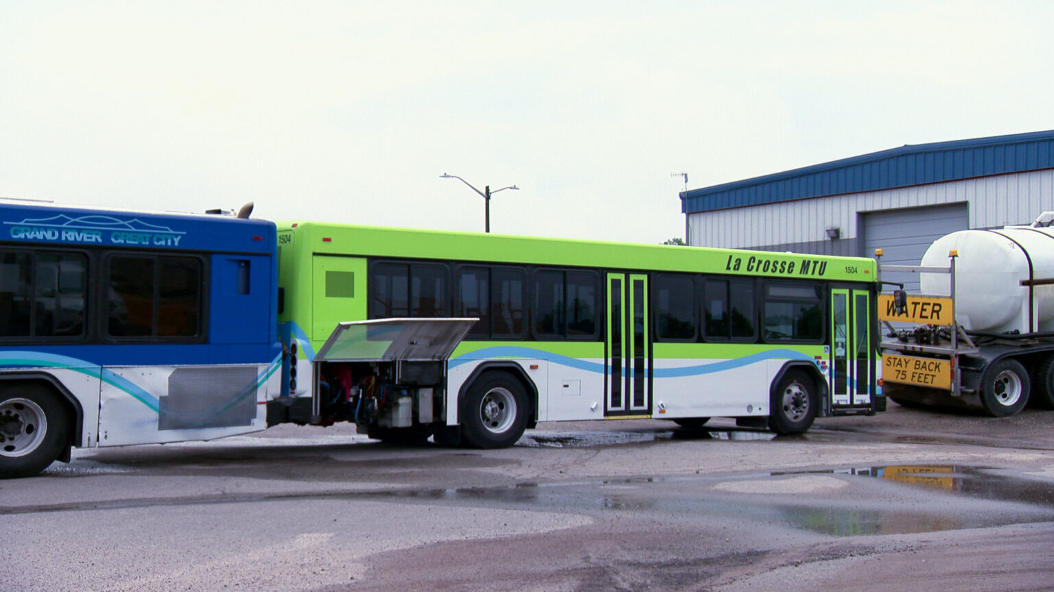 A La Crosse MTU bus sits parked in behind a water truck.