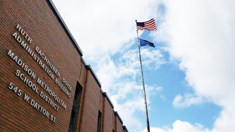 A view of the Madison Metropolitan School District administrative office building with a flag pole flying the USA and Wisconsin flags