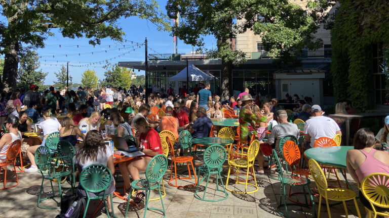 A crowd sits at tables on a sunny day at the Memorial Union Terrace.