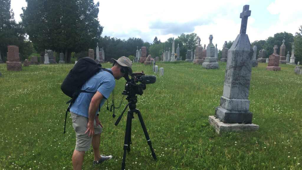 A camera crew films a grave