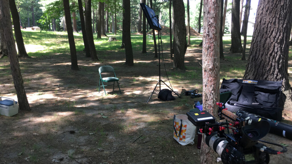 A chair and camera equipment set up for an interview in the woods