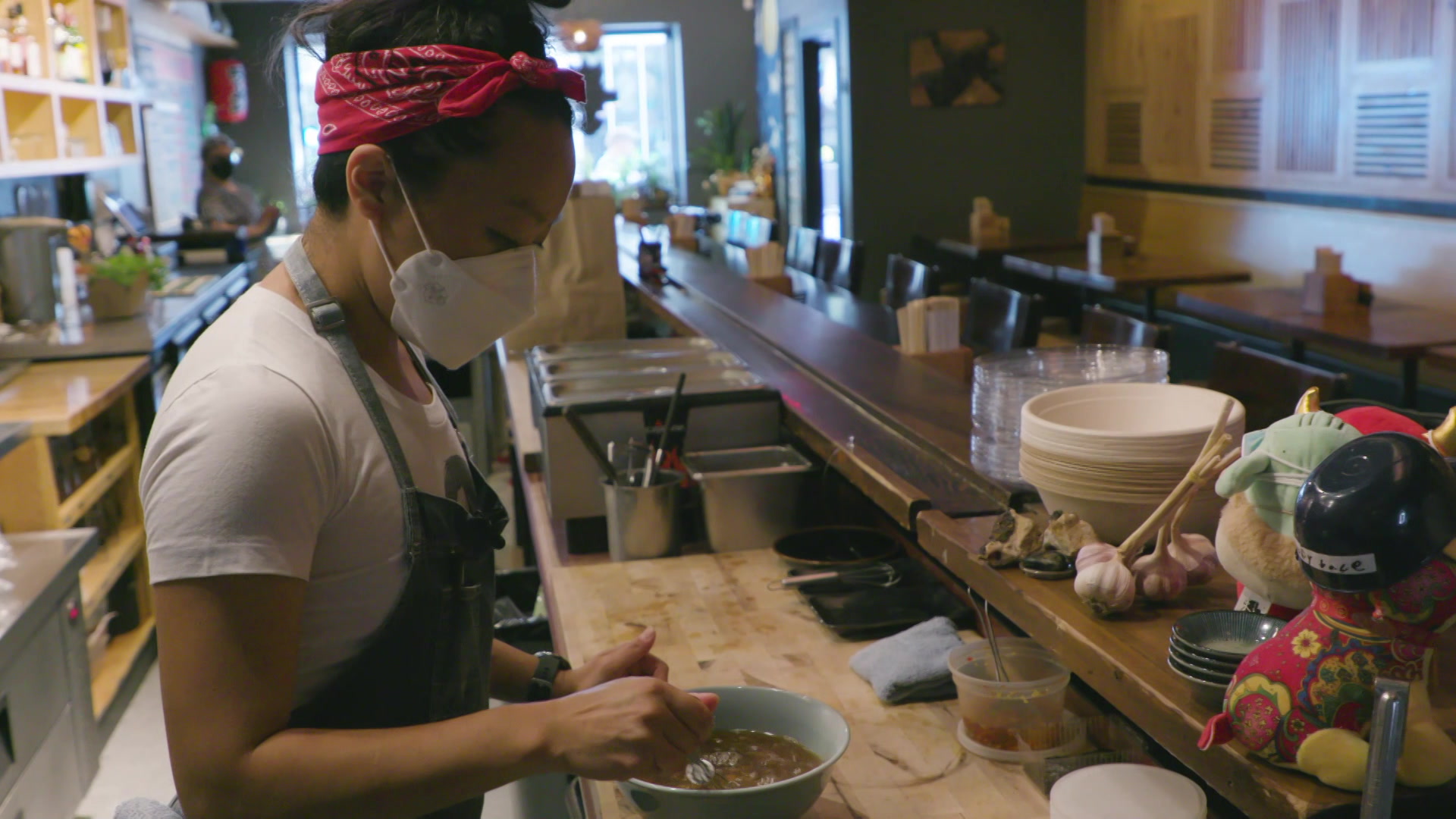 Francesca Hong stands behind a restaurant counter and prepares a bowl of soup.