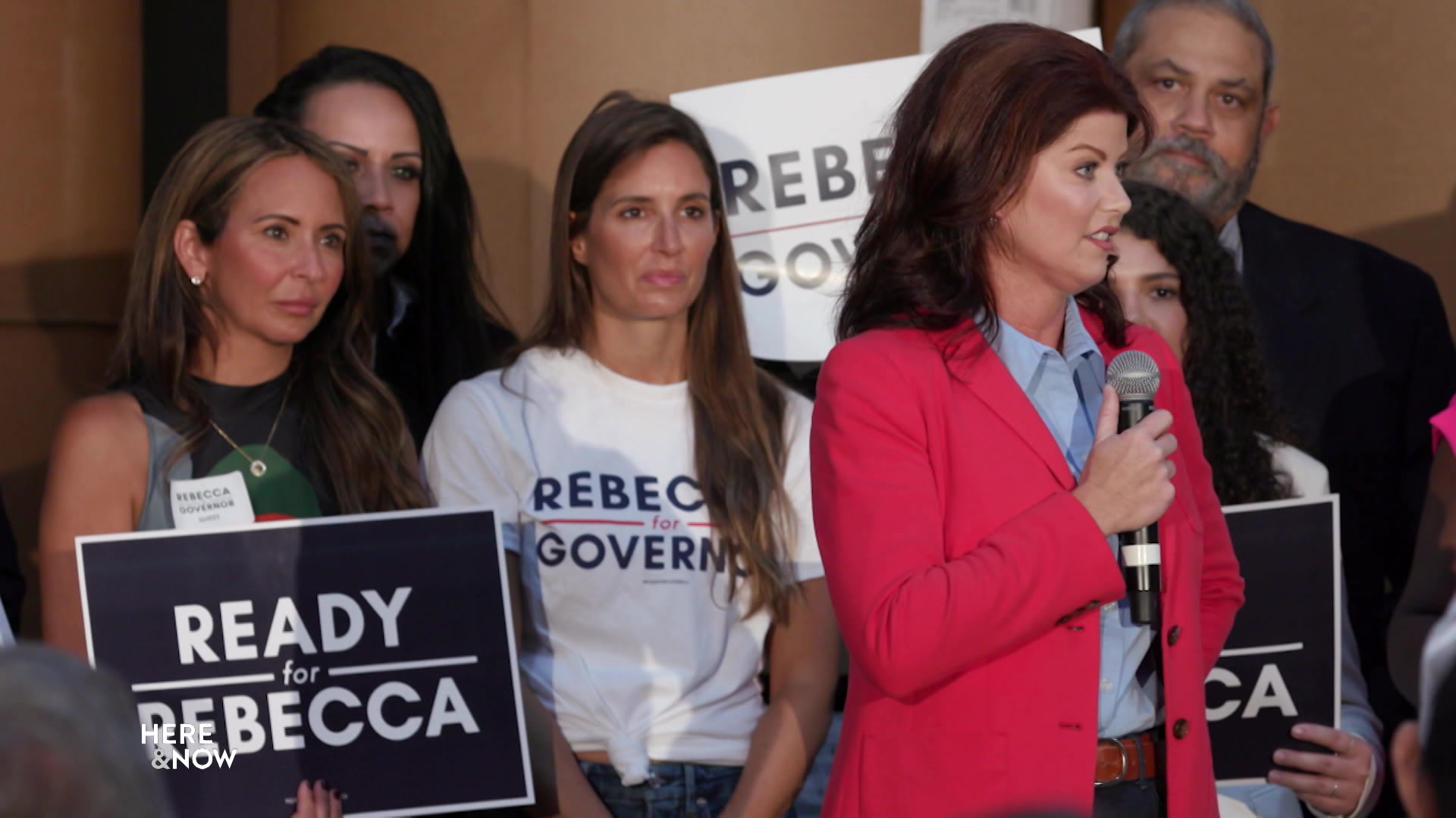 From left, Scarlett Johnson (holding a "Ready for Rebecca" sign) and Amber Schroeder (wearing a "Rebecca for Governor" shirt) stand behind Republican candidate for governor and former Lt. Gov. Rebecca Kleefisch at a political rally.