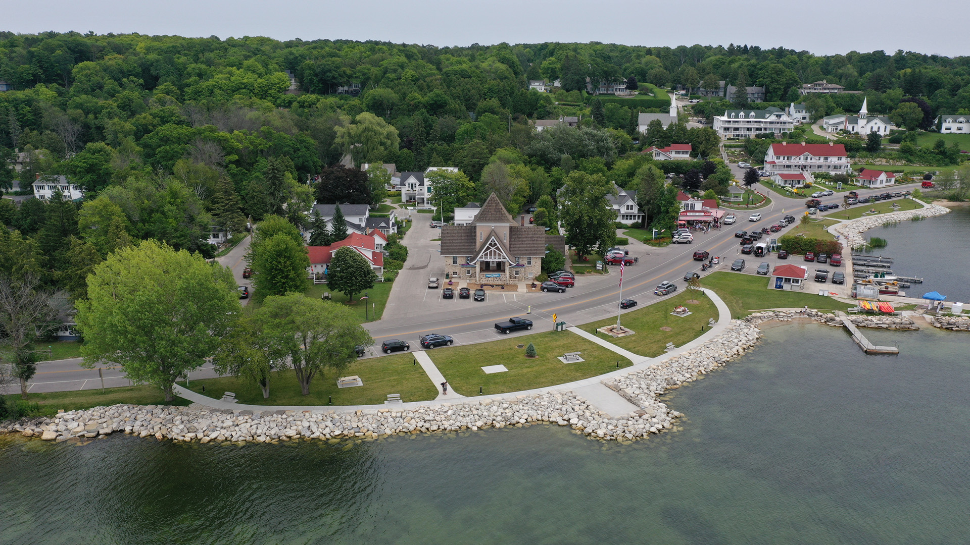 An aerial photo shows the shoreline, roads, buildings and trees.