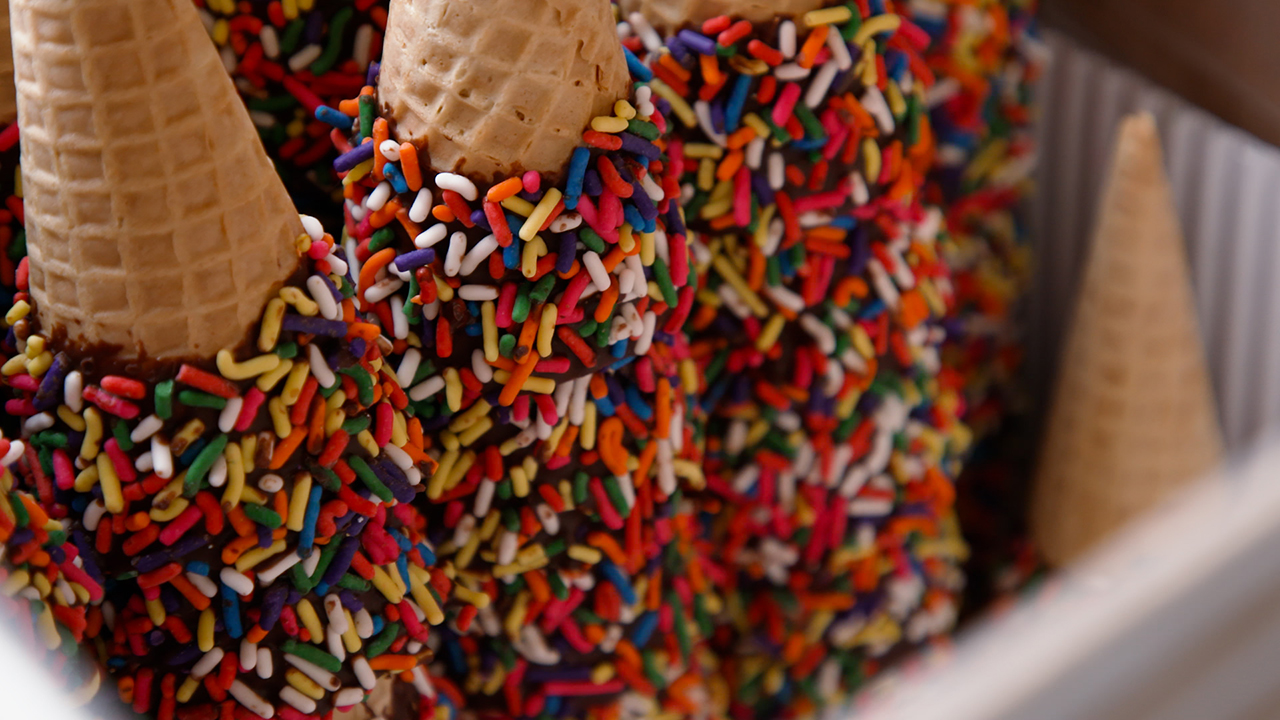 A stack of ice cream cones that have been dipped in chocolate and sprinkles.