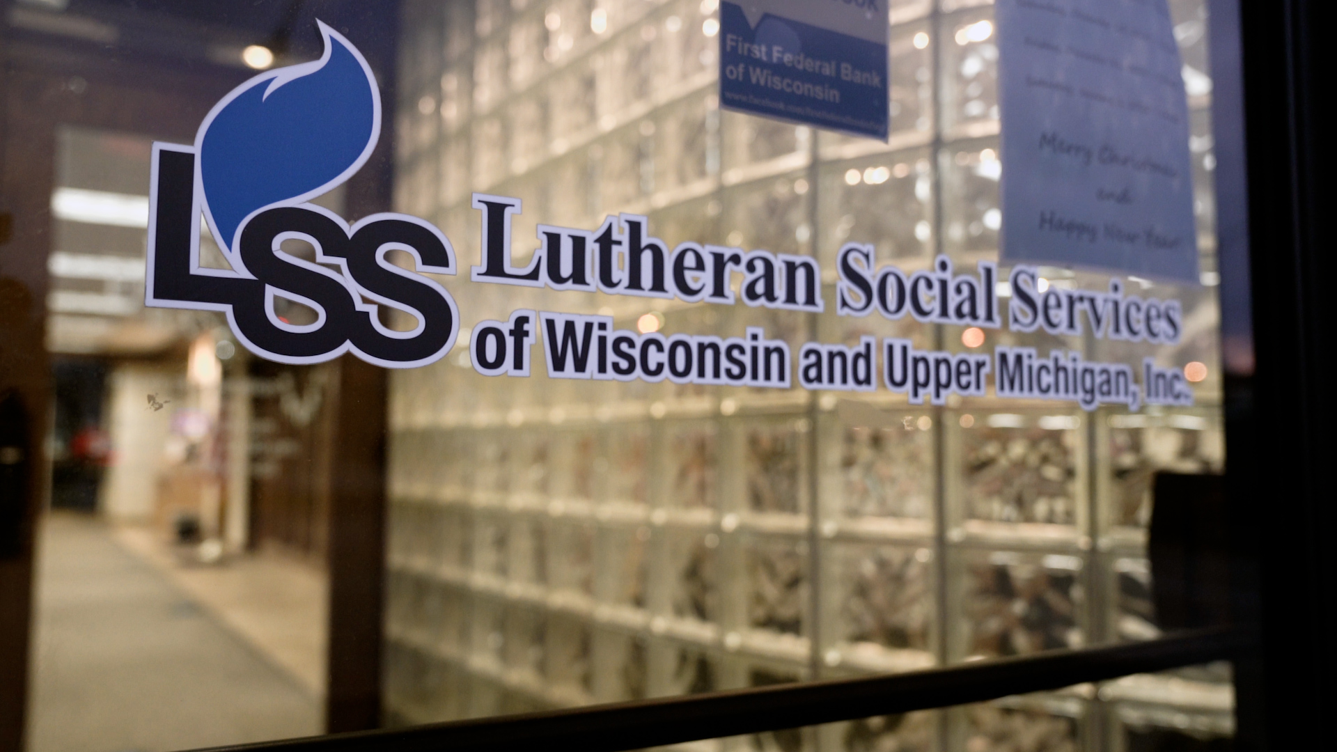 A painted door sign stencil reads "Lutheran Social Services of Wisconsin and Upper Michigan, Inc."