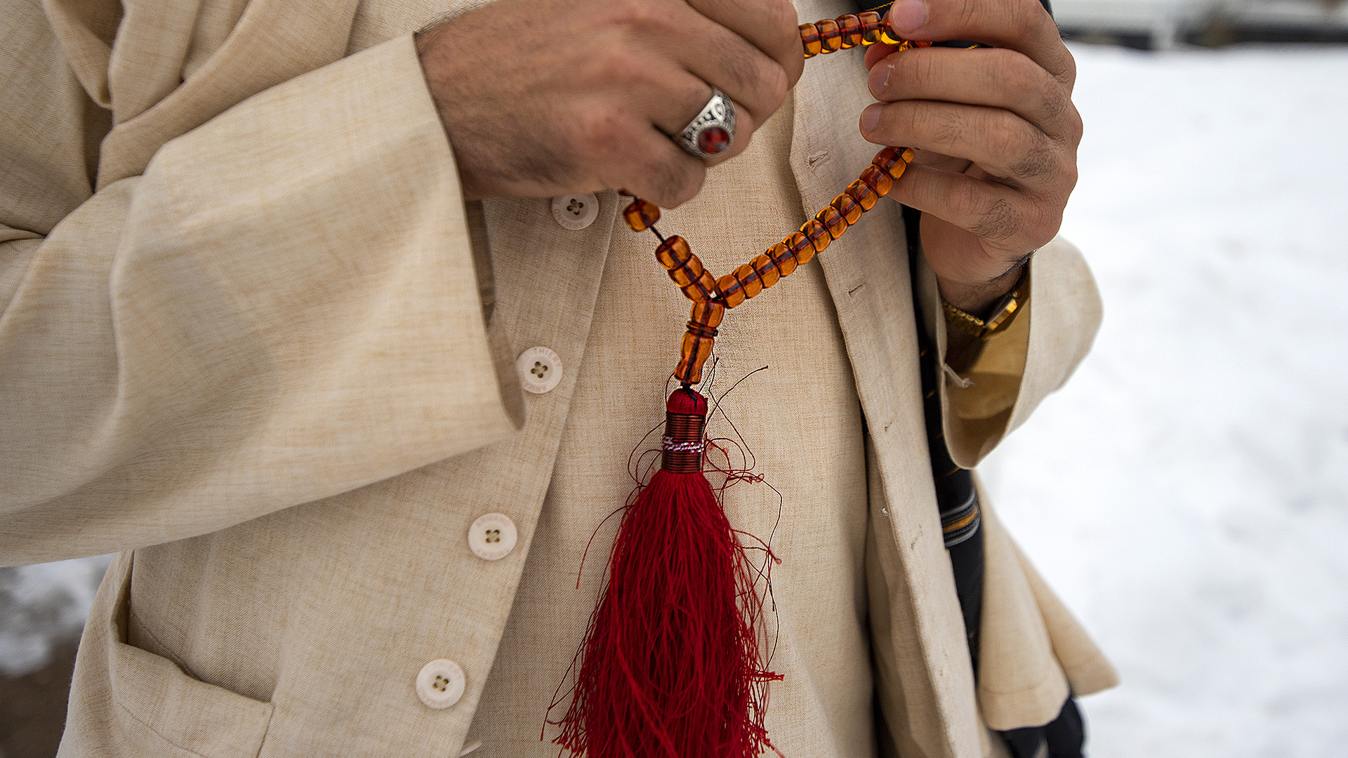 Matiullah Matie holds red beads on a string with a red tassel connected to them.