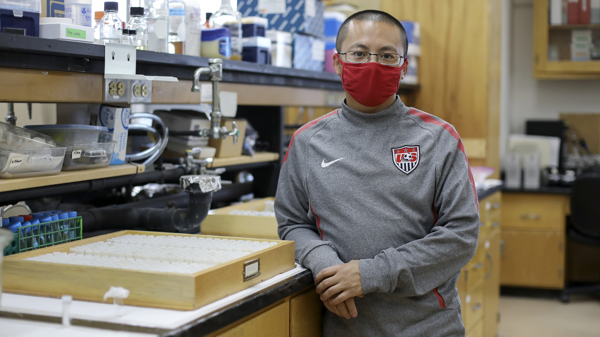 Xia Lee stands next to a bench in a laboratory.
