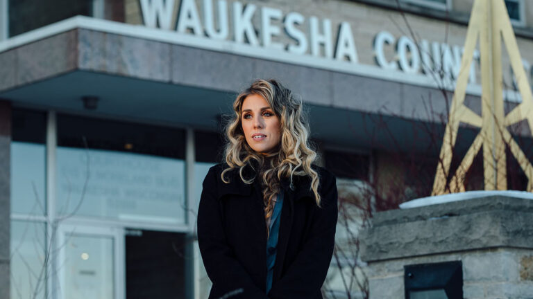 Julie Valadez stands in front of a building with the sign Waukesha County Courthouse.