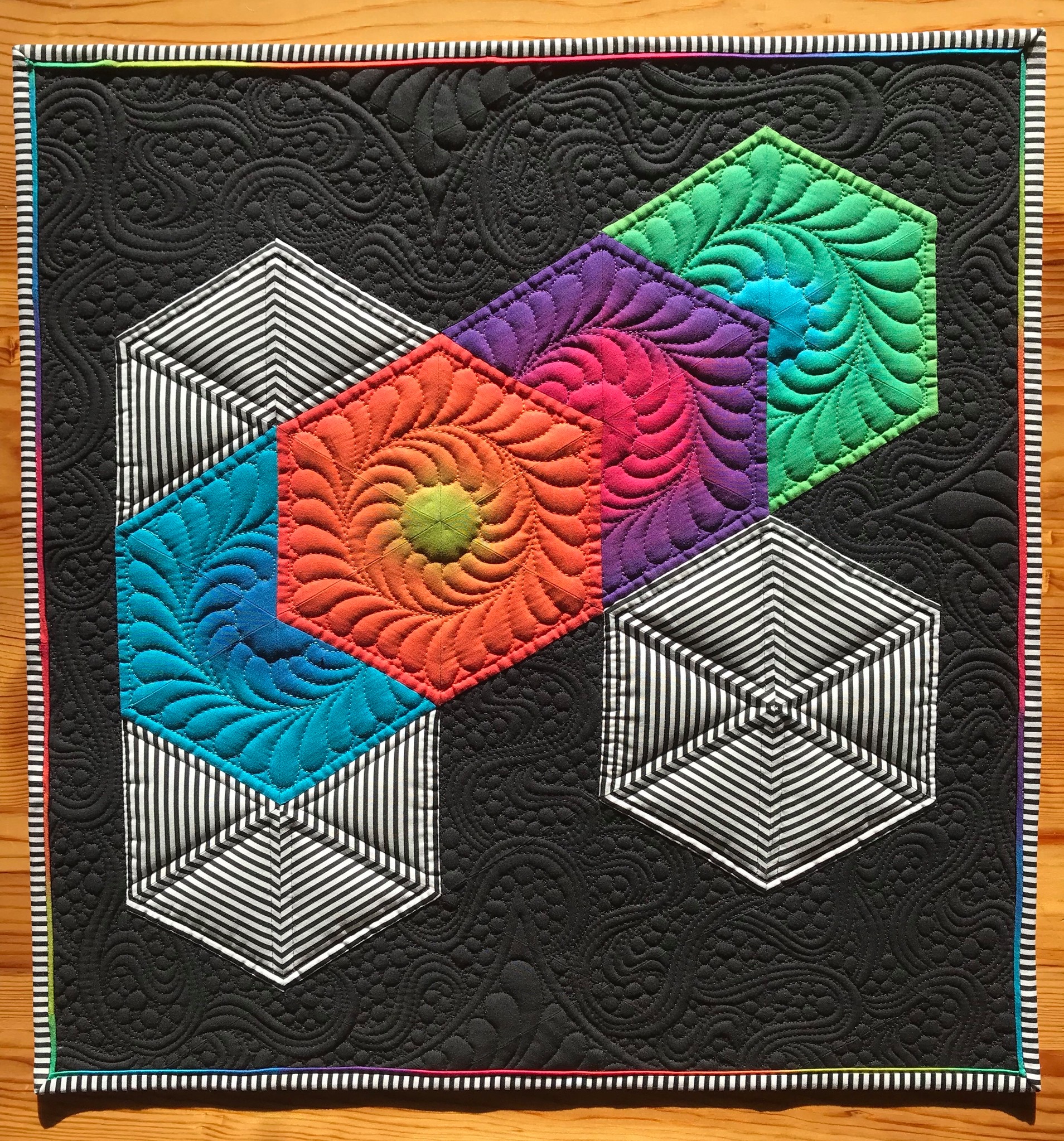 Prisms of colorful fabric with detailed stitching on a black background