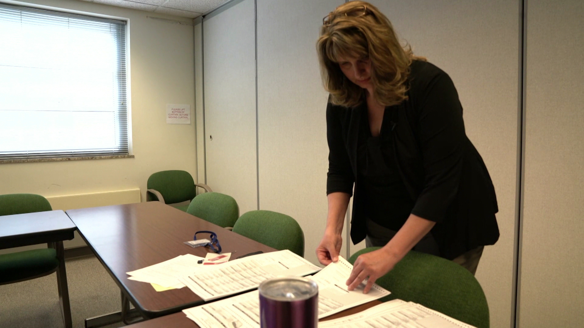 Lisa Tollefson stands in a conference room, paging through stacks of papers on a table.