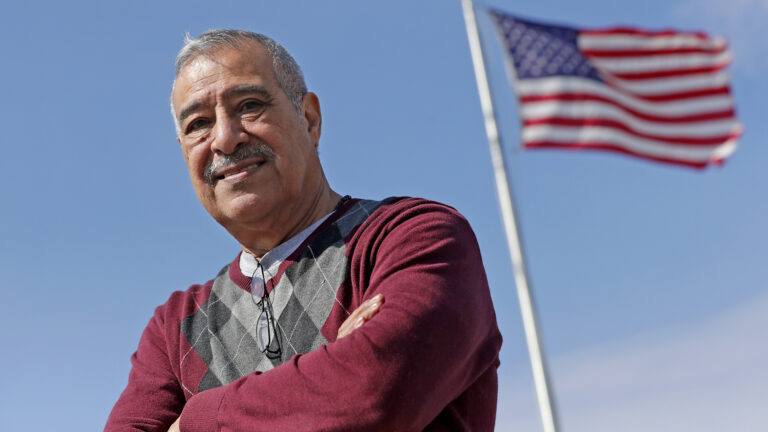 Ernesto Gonzalez Jr. stands outside with an American flag in the background.