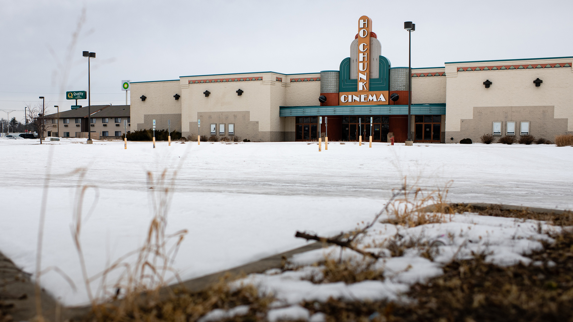 A movie theater with a marquee reading "Ho Chunk Cinema" faces a snow-covered empty parking lot.