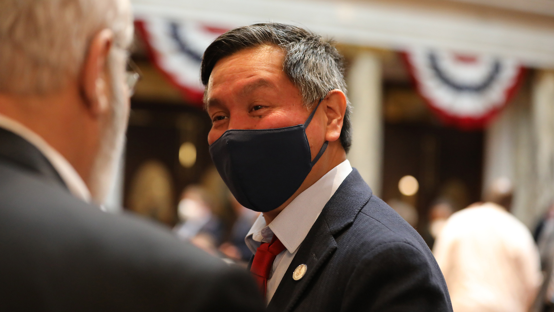 Marlon WhiteEagle wears a face mask while speaking to another person in the Wisconsin Capitol.