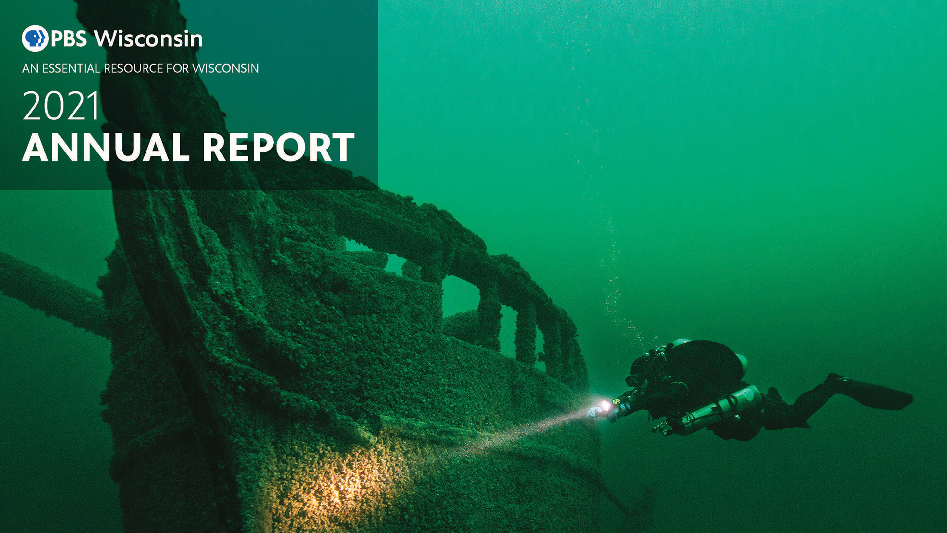A cover of the PBS Wisconsin 2021 Annual Report featuring a sunken ship in The Great Lakes with a diver swimming close to it shining a flashlight