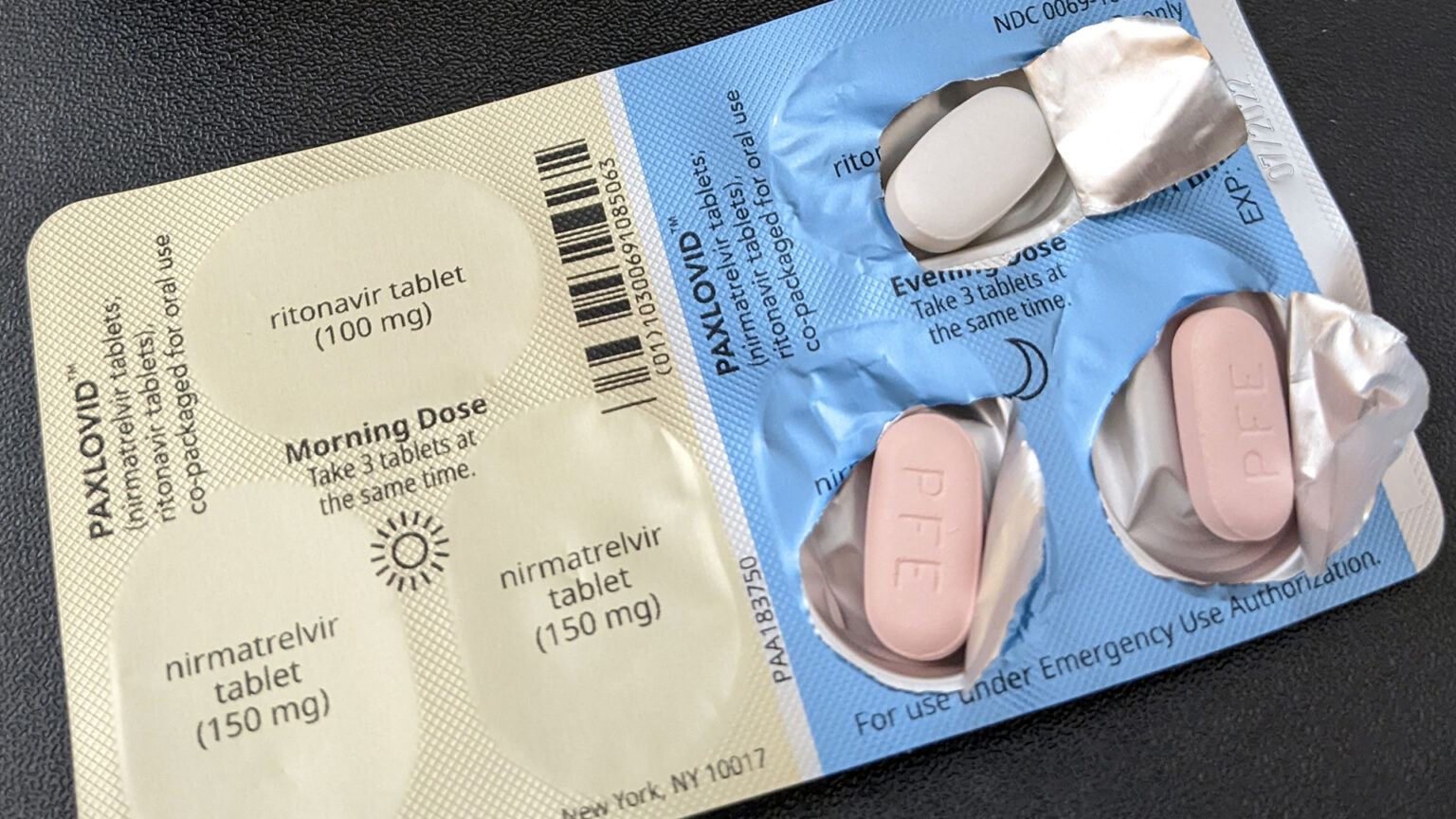 A pack of Paxlovid sits on a table with the evening doses opened to show the pills.