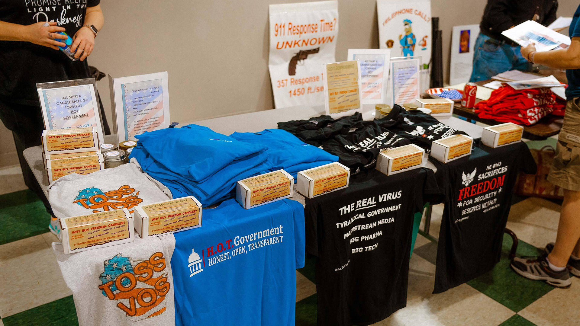 T-shirts stating "Toss Vos," "H.O.T. Government" and other political slogans sit for sale on a table.