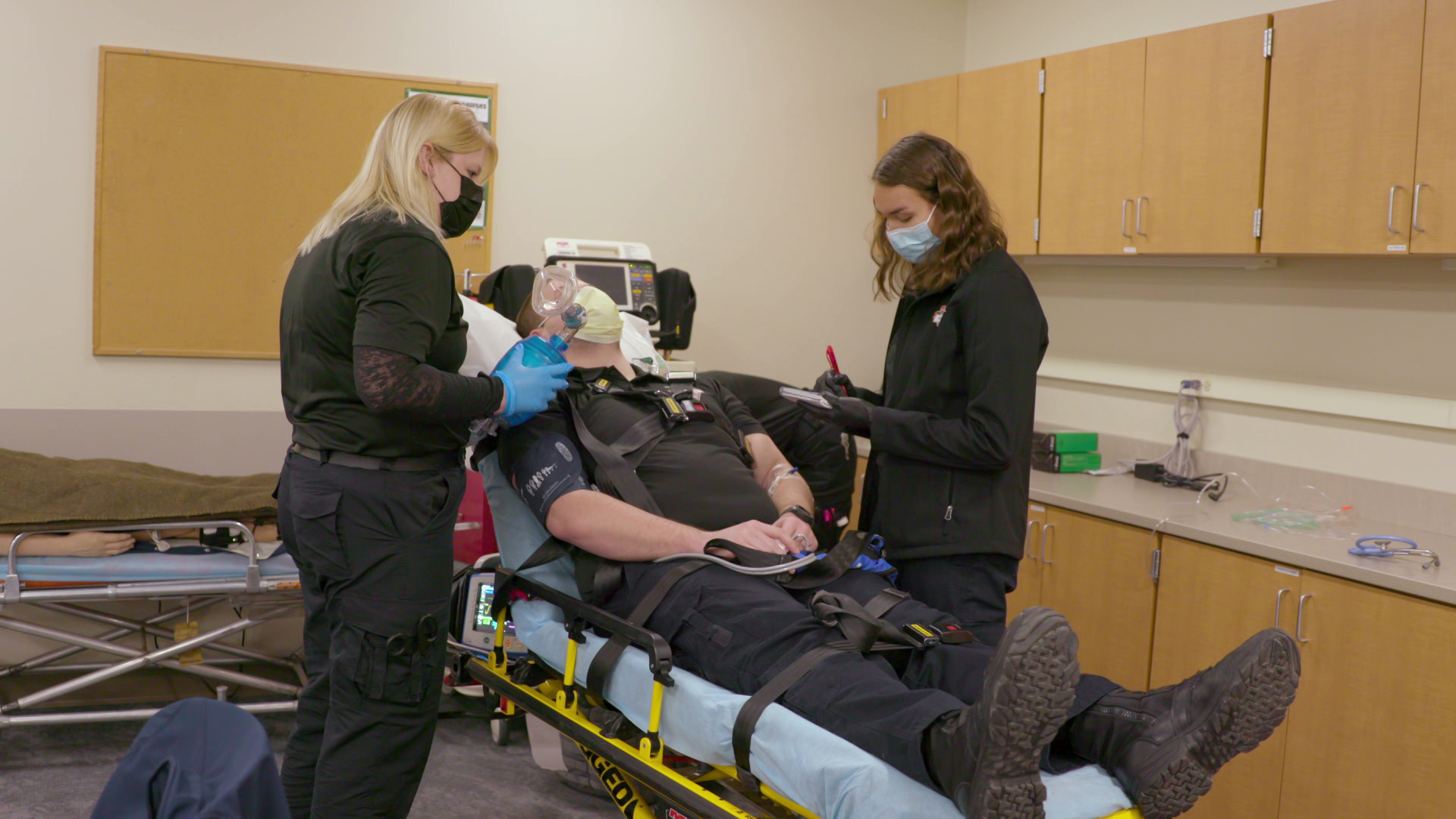 Jenna Quakenbush trains to be a paramedic and stands over another student who is strapped into a gurney at Western Technical College in La Crosse.