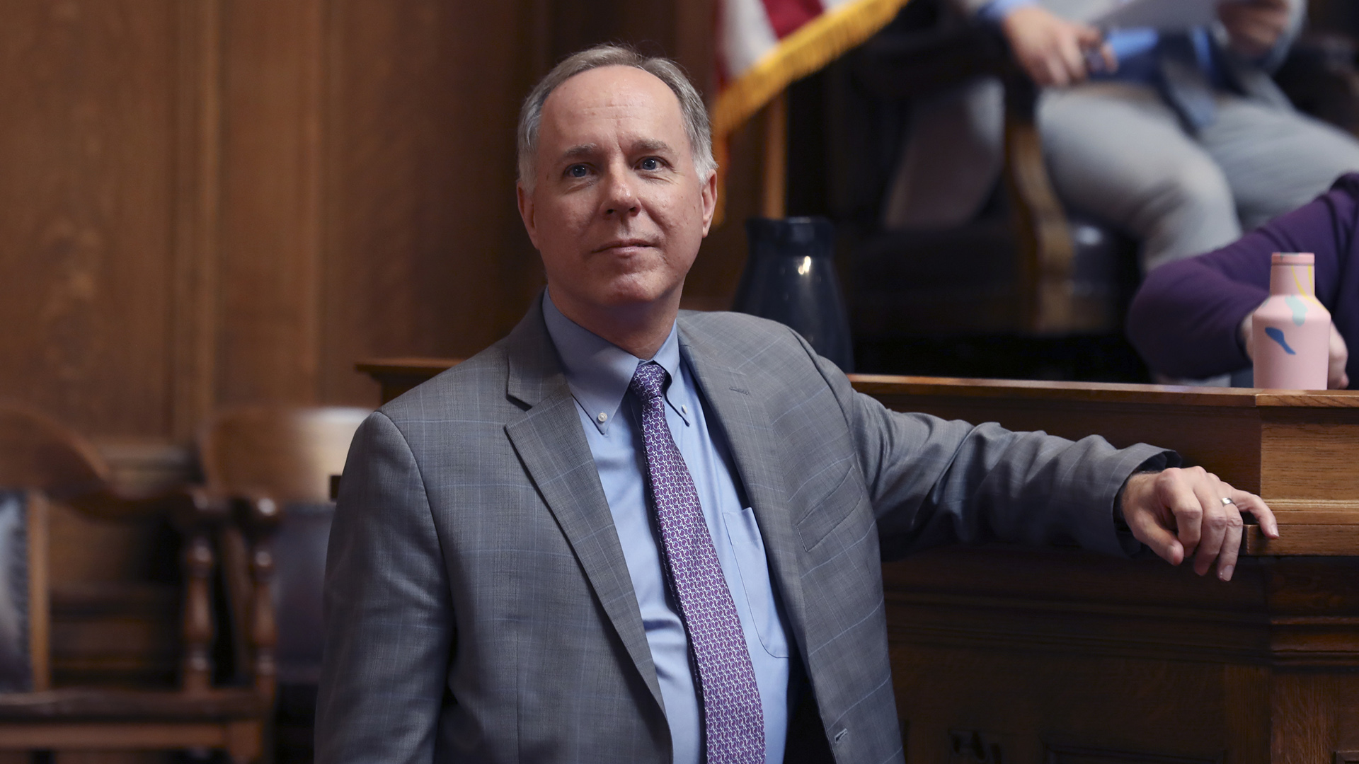 Robin Vos stands in a room with wood-paneled walls with his arm resting on the edge of a dais.