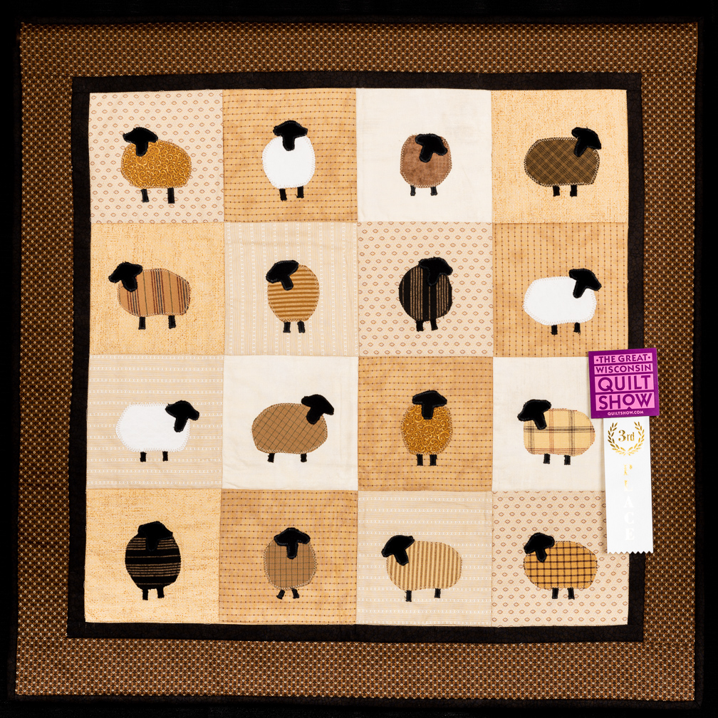 A quilt decorated with a grid of geometric sheep