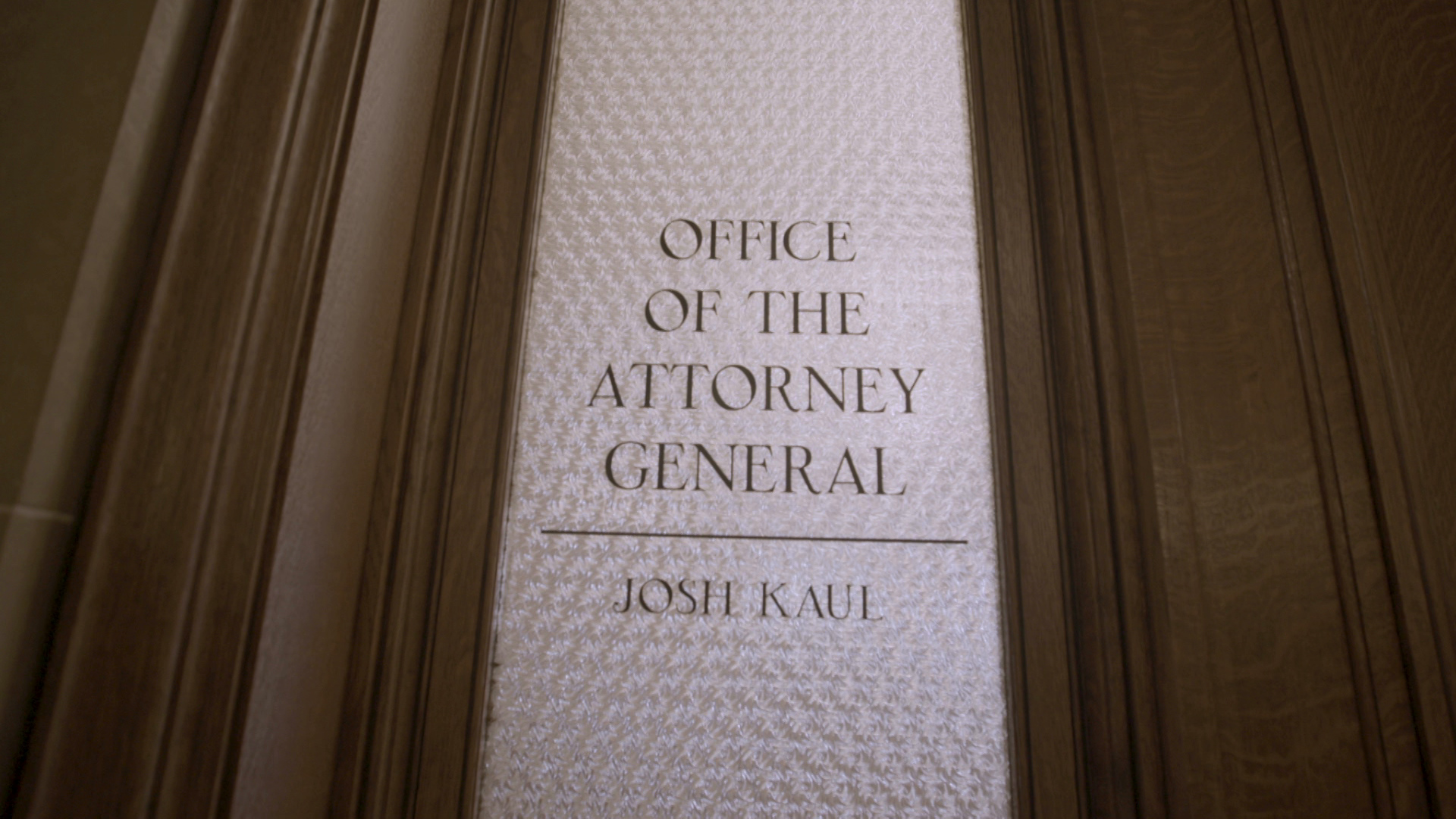 A stenciled sign painted on a frosted glass door reads "Office of the Attorney General Josh Kaul."