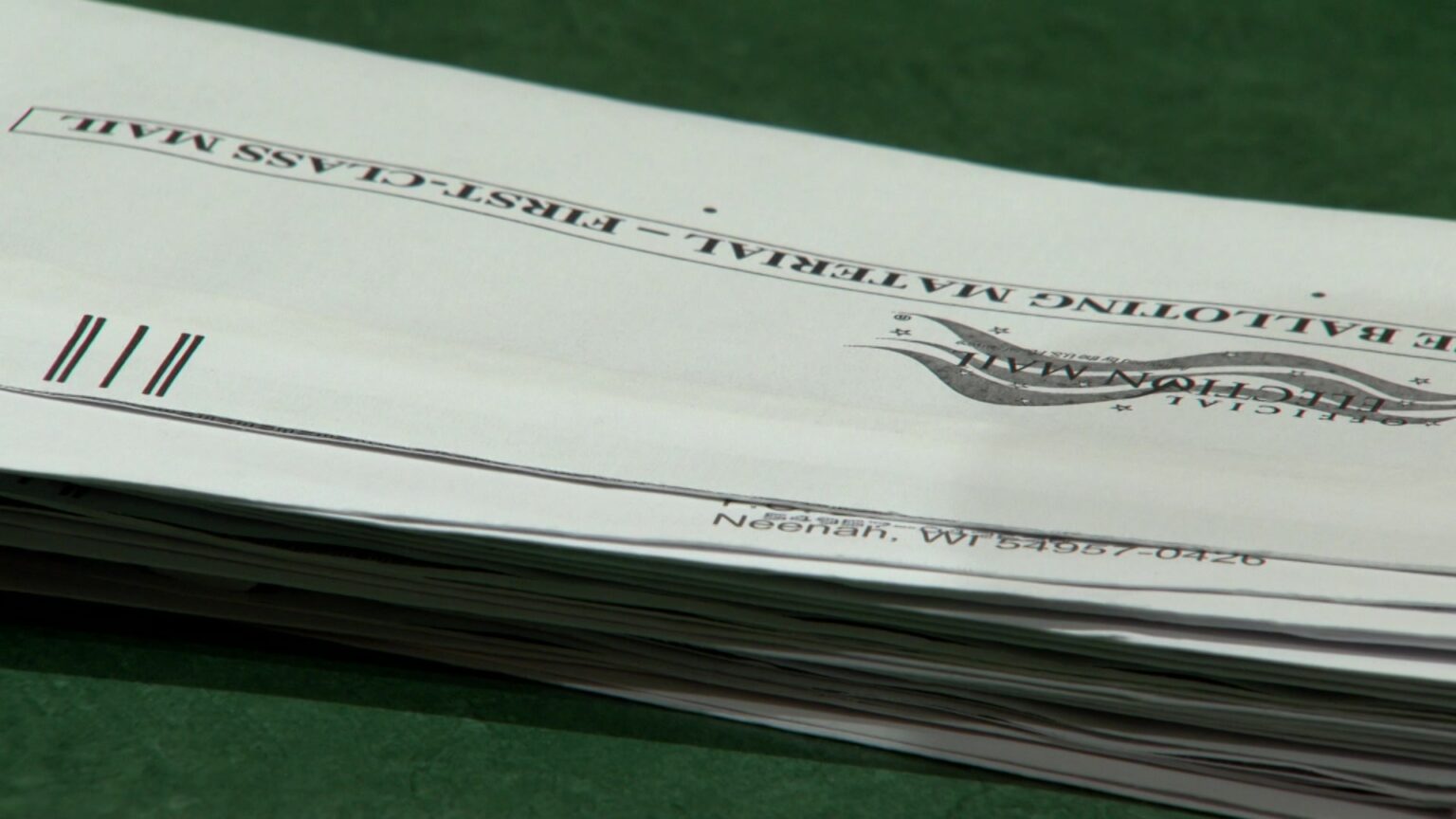 A stack of absentee ballot envelopes sits on top of a table.