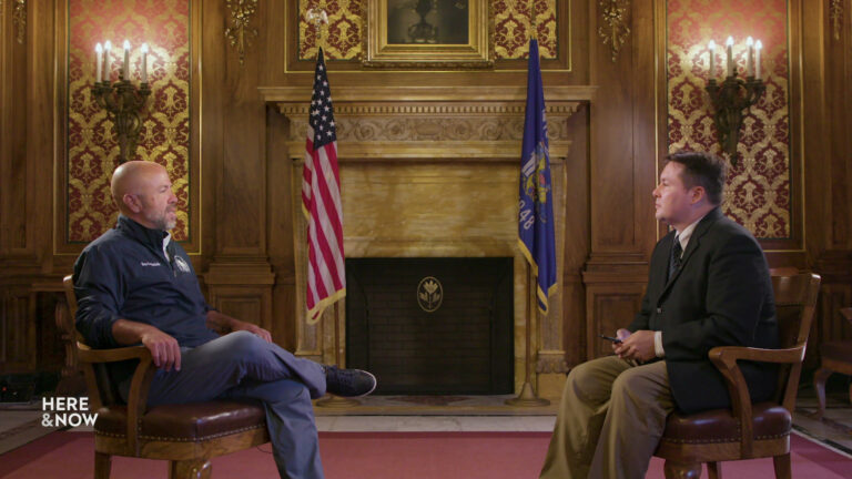 Jim Steineke and Zac Schultz sit in chairs in a room in the Wisconsin State Capitol with a wood-paneled fireplace, sconces and the U.S. and state flags in the background.
