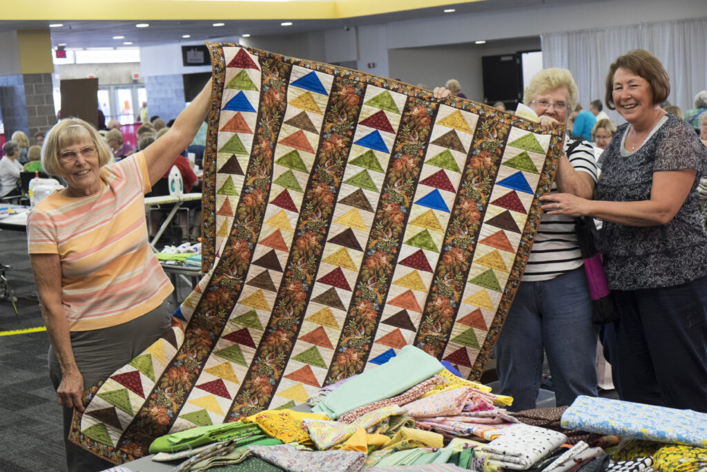 Women holding up a quilt they made together