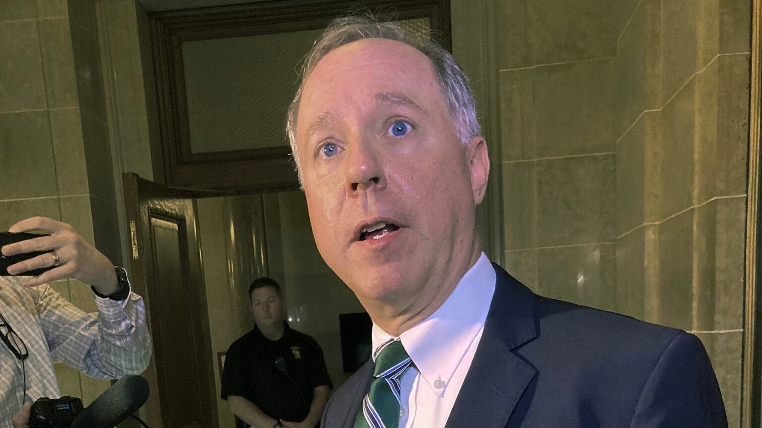 Robin Vos answers questions while standing in a hallway with marble-block walls.